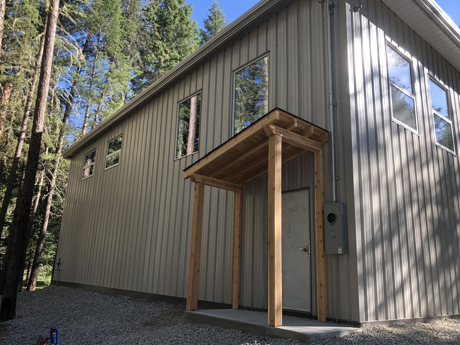Grey steel building with a timber entry porch and upper windows