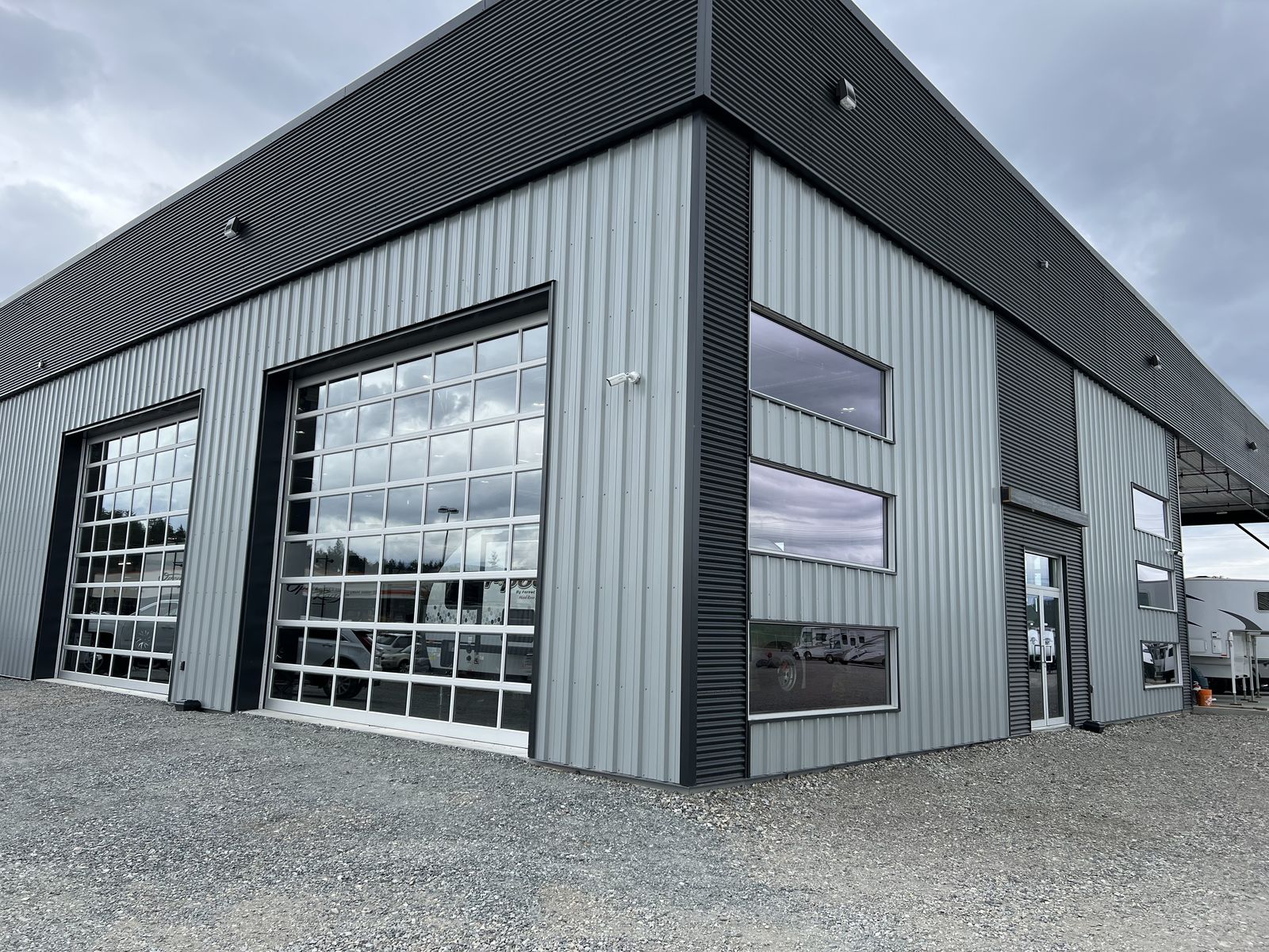 Grey steel building with dark trim and glass overhead doors