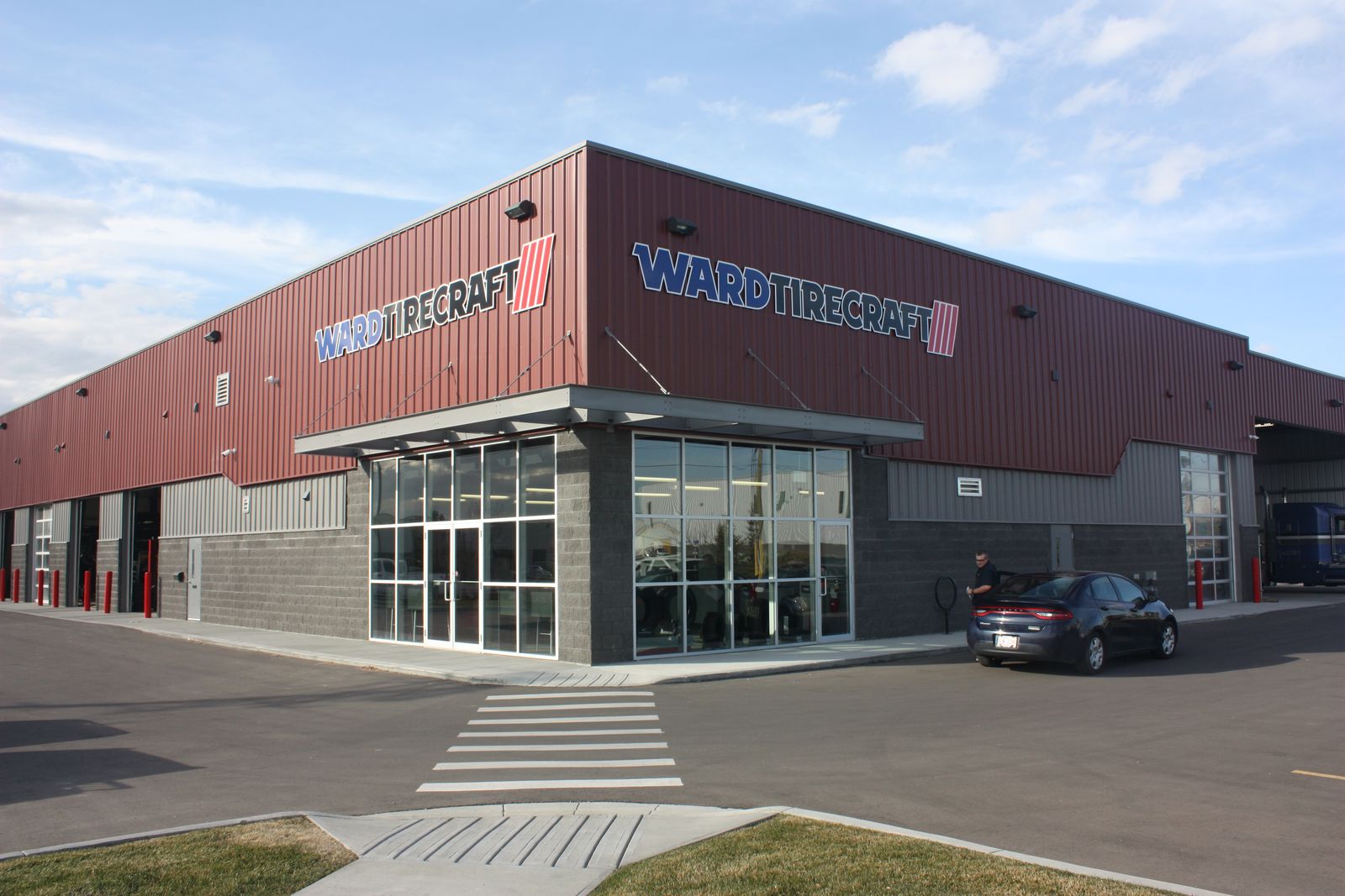 Red and grey commercial steel building with a glass storefront entrance