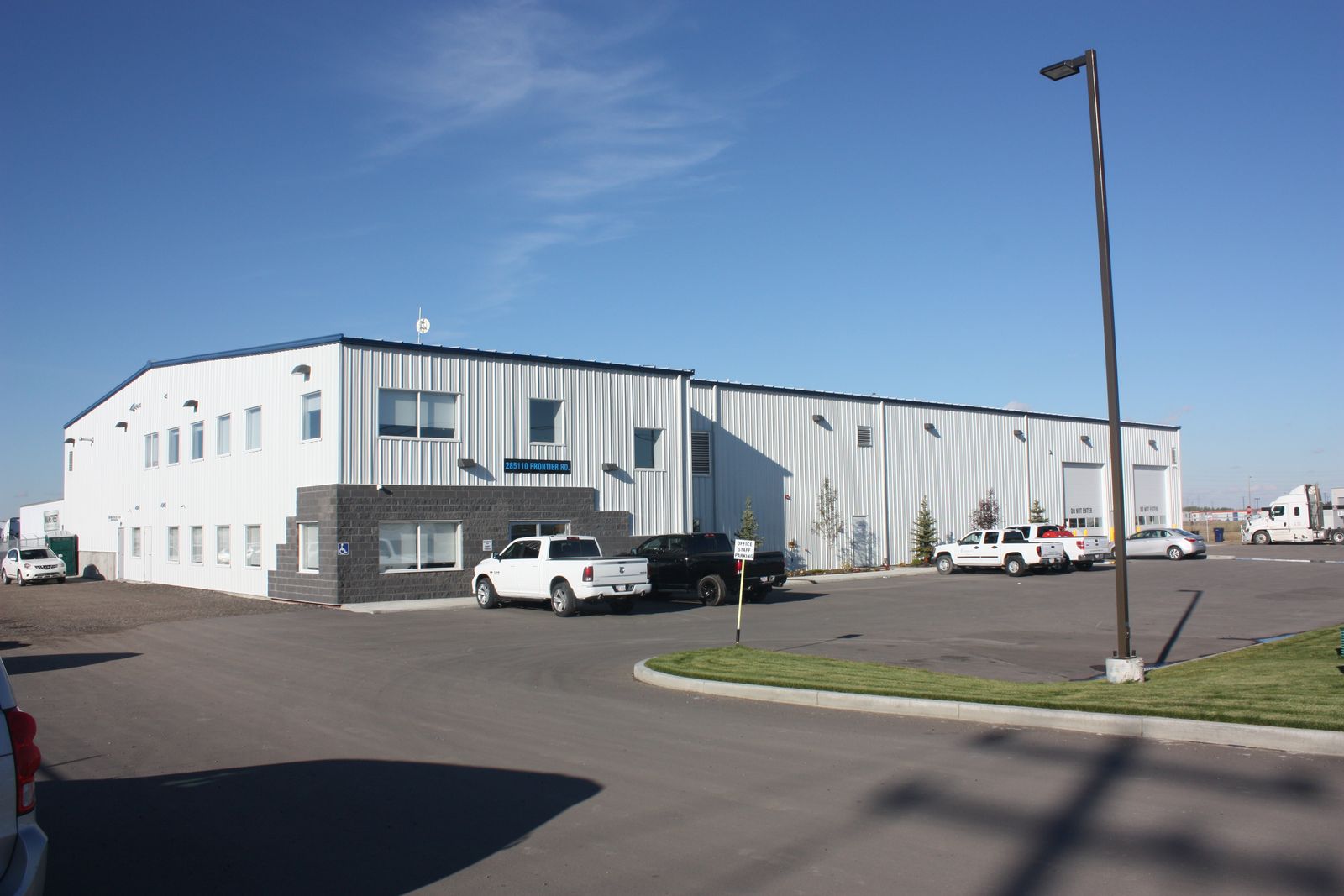 White two-storey steel office and warehouse building with trucks parked out front
