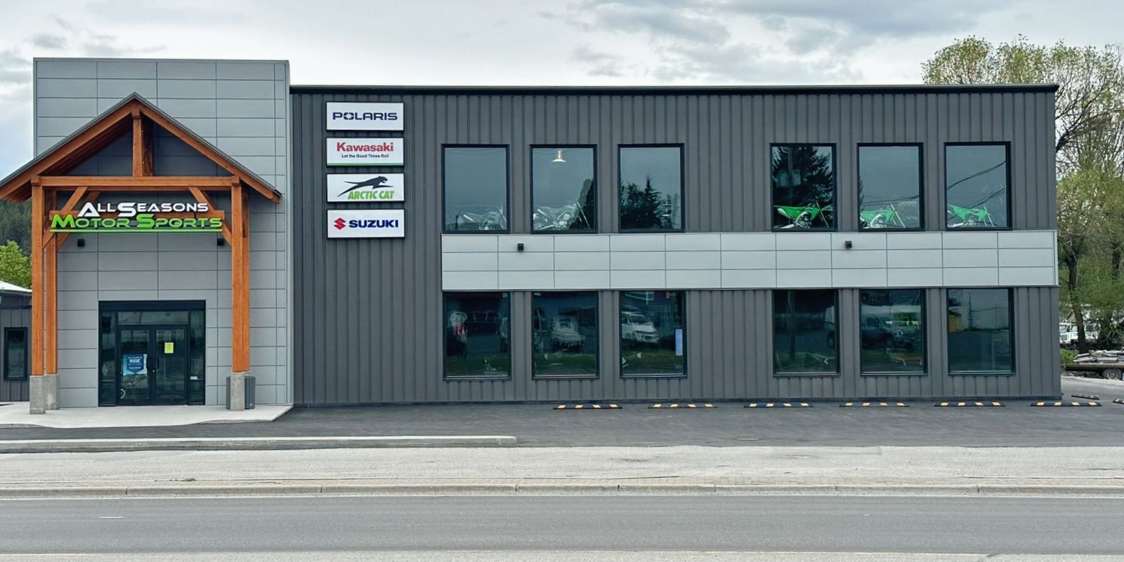 Grey commercial steel building with a timber-framed entrance and storefront windows