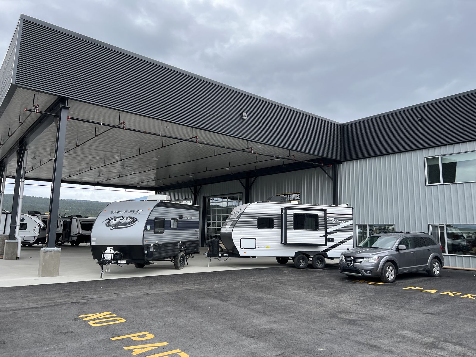 Steel canopy over parked RVs beside a grey steel building