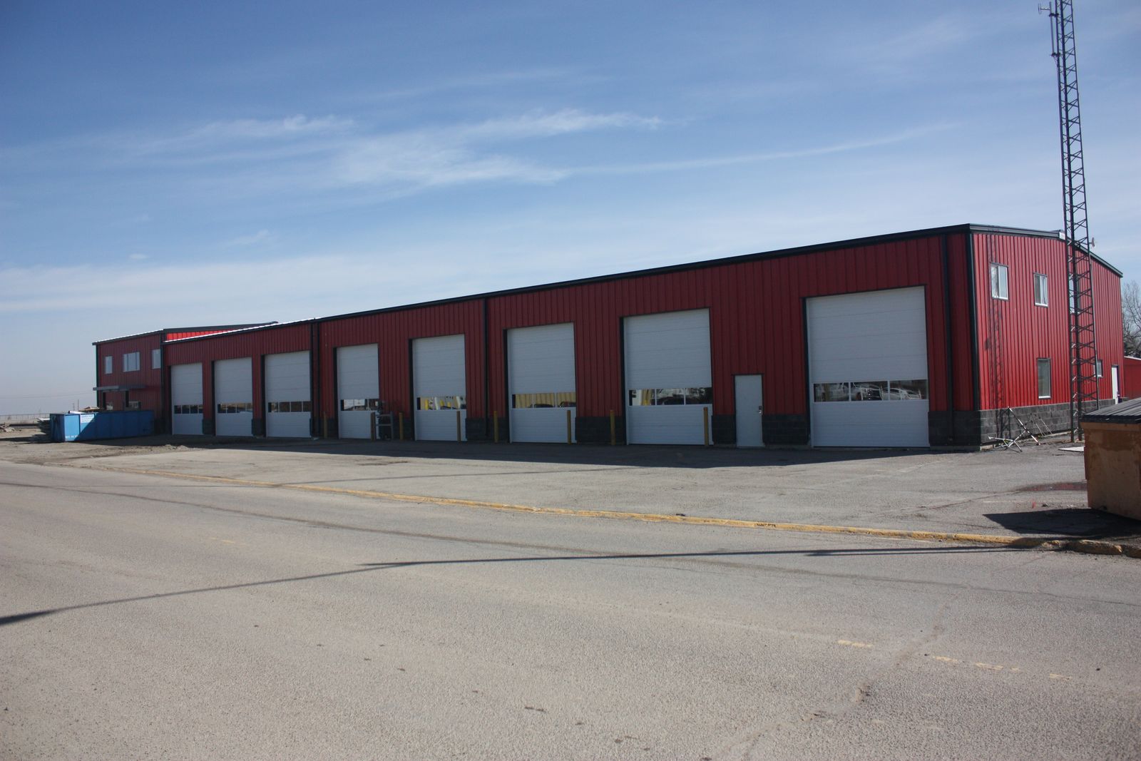 Long red steel building with a row of white overhead doors