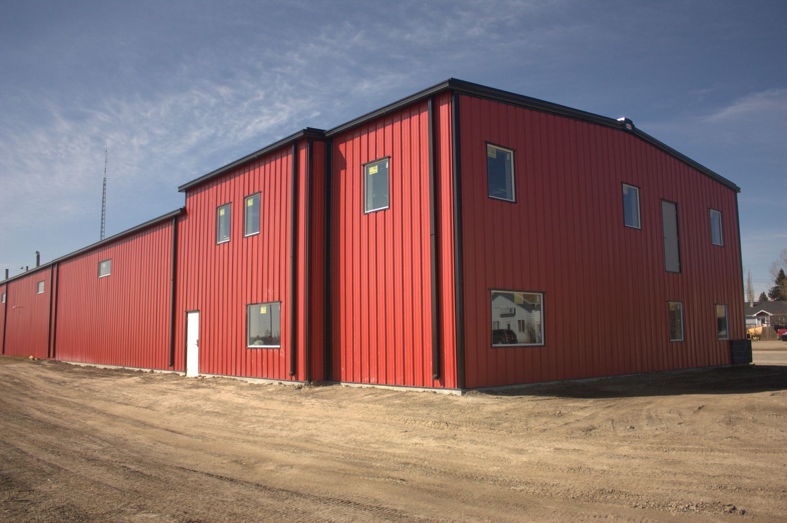 Two-storey red steel building with windows and an attached lower section